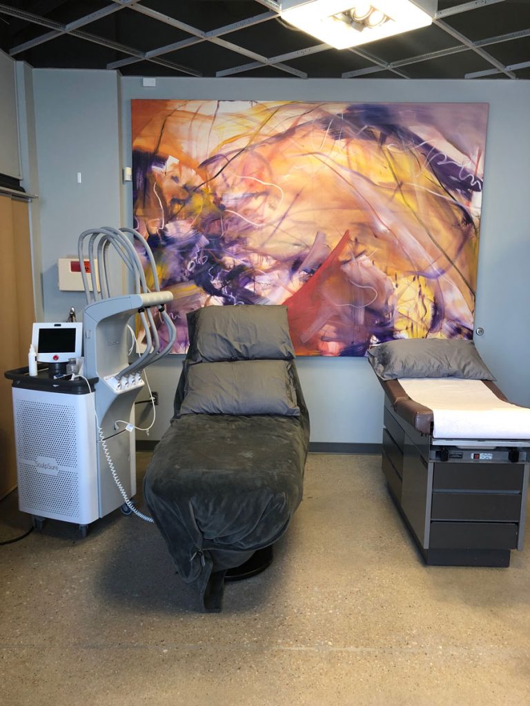 PMC treatment room with 2 reclining tables and modern art on the wall