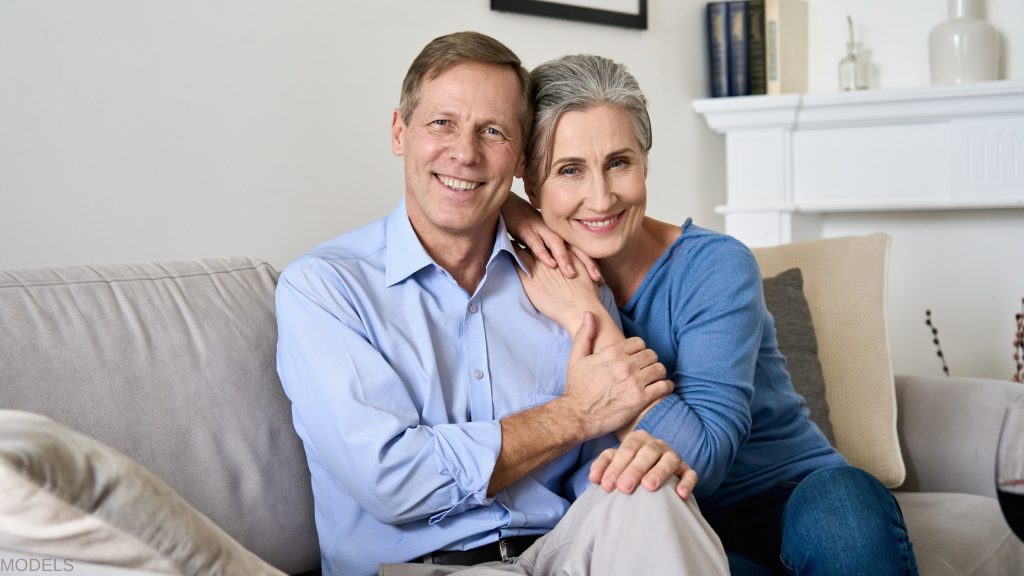 older couple smiling on the couch after starting HRT (models)
